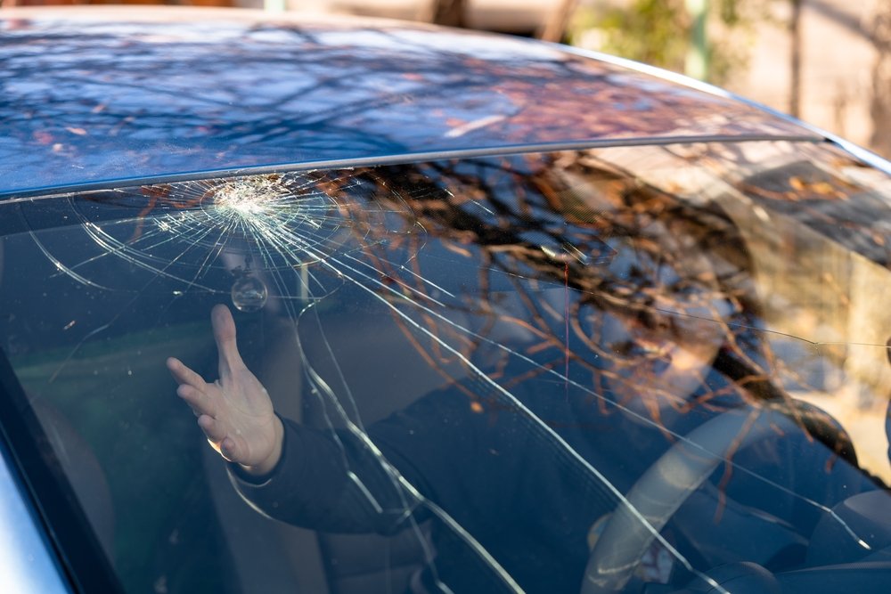 Shocked Woman In Car With Broken Windshield And Cracks