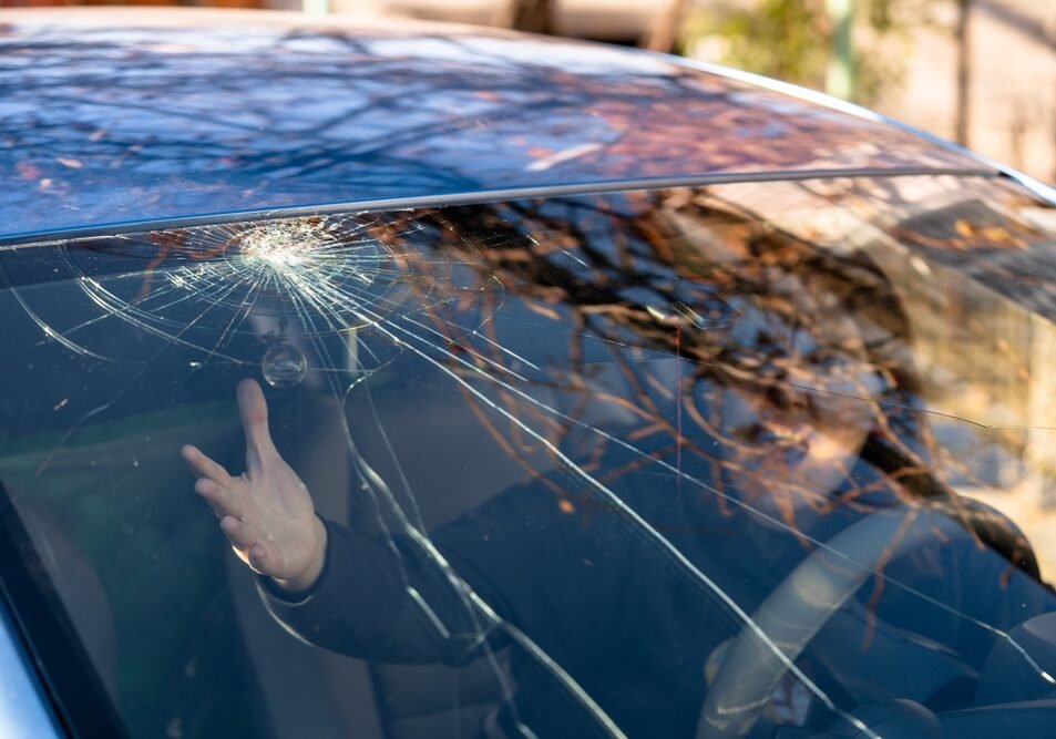 Shocked Woman In Car With Broken Windshield And Cracks
